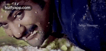 a man is laying on a bed with rice on his face and looking at the camera .