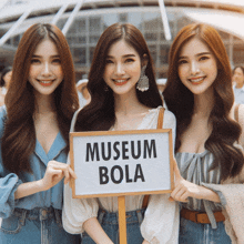 three women hold a sign that says museum bola