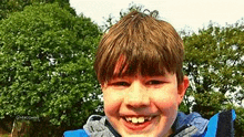 a young boy wearing a blue jacket is smiling for the camera .