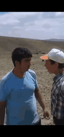 two men are standing next to each other on a dirt road .