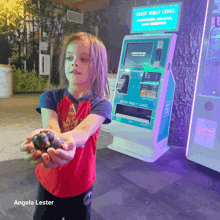 a little girl is holding a ball in front of a great wolf lodge machine