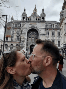 a man and woman are kissing in front of a building that has a sign that says ' astrid ' on it