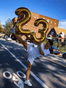 a man holds up a balloon that says 23 on it