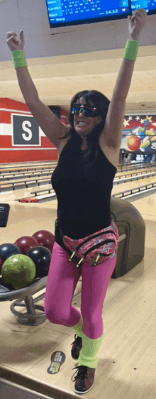 a woman jumps in the air at a bowling alley with a sign that says s on it