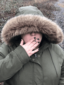 a woman in a parka with a fur hood covering her mouth