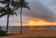 a sunset on a beach with palm trees and chairs in the foreground