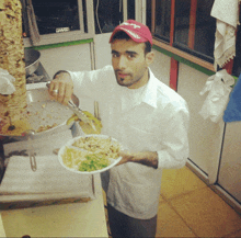 a man in a red hat is holding a plate of food with a knife and fork