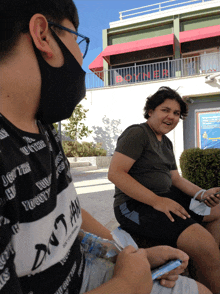 a boy wearing a black face mask is sitting in front of a boyner store