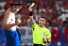 a referee holds up a yellow card in front of a shirtless man