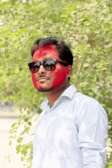 a man wearing sunglasses has red paint on his face