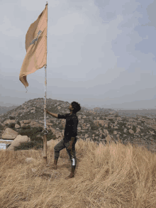 a man stands on a hill holding a flag that says ' aa ' on it