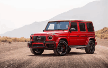 a red mercedes benz is parked on a dirt road