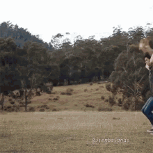 a man is carrying another man on his shoulders in a field with trees in the background and the caption jiembasands