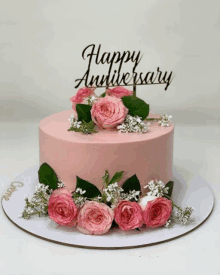 a pink cake with pink roses and baby 's breath and a happy anniversary topper