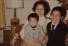 a family is posing for a picture while sitting on a couch and smiling .