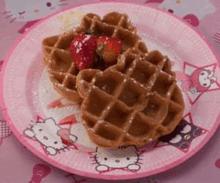 two waffles with strawberries on top of them on a pink hello kitty paper plate .