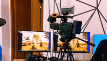 a video camera is sitting on a tripod in front of two computer monitors