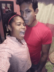 a man in a red shirt is standing next to a girl with her tongue out