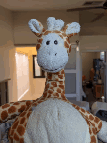 a stuffed giraffe is sitting in a room with a ceiling fan