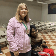 a woman in a pink jacket is standing next to a man in a wheelchair wearing a shirt that says clash