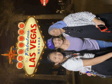 three people posing in front of a sign that says welcome to fabulous las vegas nevada