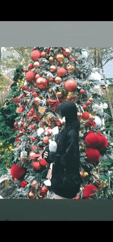 a woman standing in front of a christmas tree holding a cup of coffee