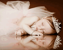 a baby wearing a tiara and a tutu is sleeping on a table