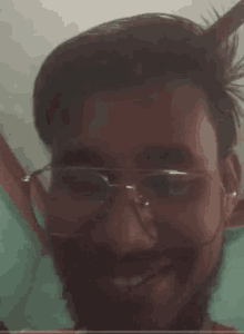 a man with glasses and a beard is smiling in a close up of his face .