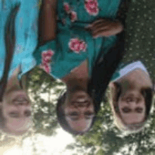 a group of three women are laying upside down in front of trees .