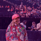 a woman wearing a pink hat stands in front of a crowd in a stadium with the number c131 visible