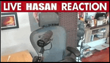 a microphone is sitting in front of a chair in a room with a sign that says live hasan reaction .