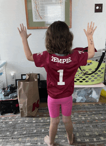 a little girl wearing a temple jersey with the number 1 on the back