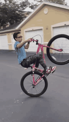 a young boy is doing a trick on a pink bicycle with the word astro on the front