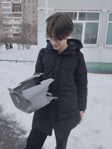 a young man in a black jacket is holding a gray object that says jeep on it