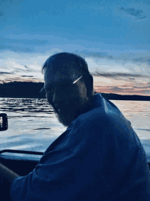 a man in a blue shirt is sitting in a boat looking at the water