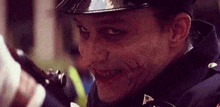 a close up of a man in a police uniform with a joker face on his face .