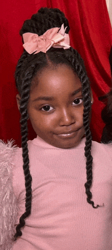 a little girl with braids and a bow in her hair