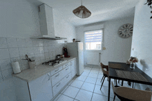 a kitchen with a table and chairs and a clock that has roman numerals on it