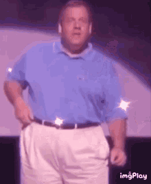 a man in a blue shirt and white shorts is dancing on a stage .