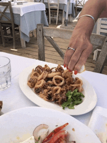 a woman 's hand is reaching for a piece of food on a white plate