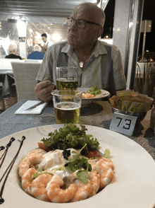 a man sits at a table with a plate of food and a number 73