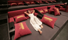 a woman in a white dress is laying on a couch with red pillows that say rudo de one