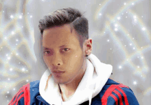 a man wearing a white hoodie and a blue and red adidas jacket