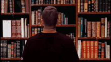 a man standing in front of a bookshelf with a book titled ' a brief history of the world '