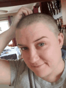 a woman with a shaved head is taking a picture of herself .