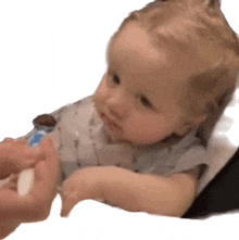 a baby is being fed by a person while looking at the camera