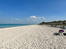 a beach with a lot of chairs and umbrellas in the sand