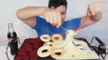 a man in a blue shirt is eating a tray of food with a bottle of coca cola on the side