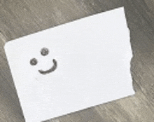 a piece of paper with a smiley face drawn on it on a wooden table .