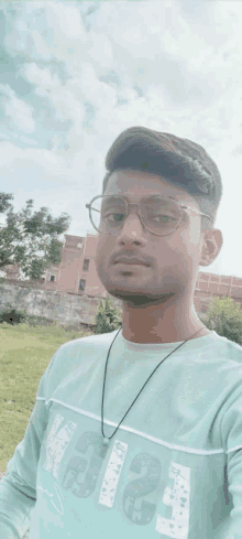 a young man wearing glasses and a green shirt with the number 1234 on it is taking a selfie